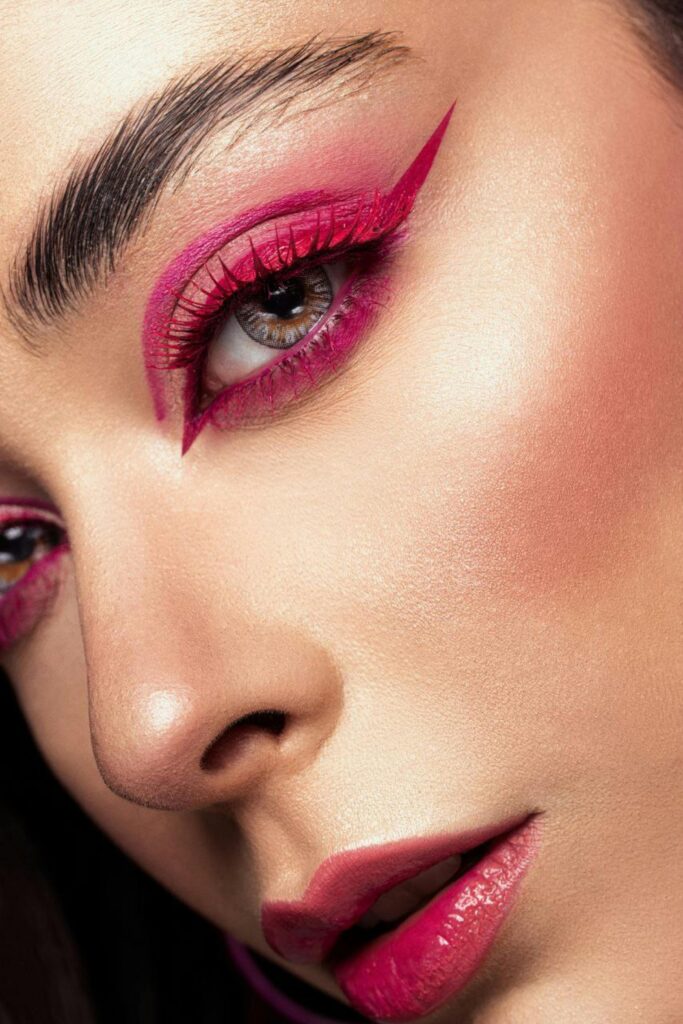 Close-up of a woman's face highlighting bold pink eyeliner and makeup in an artistic portrait.